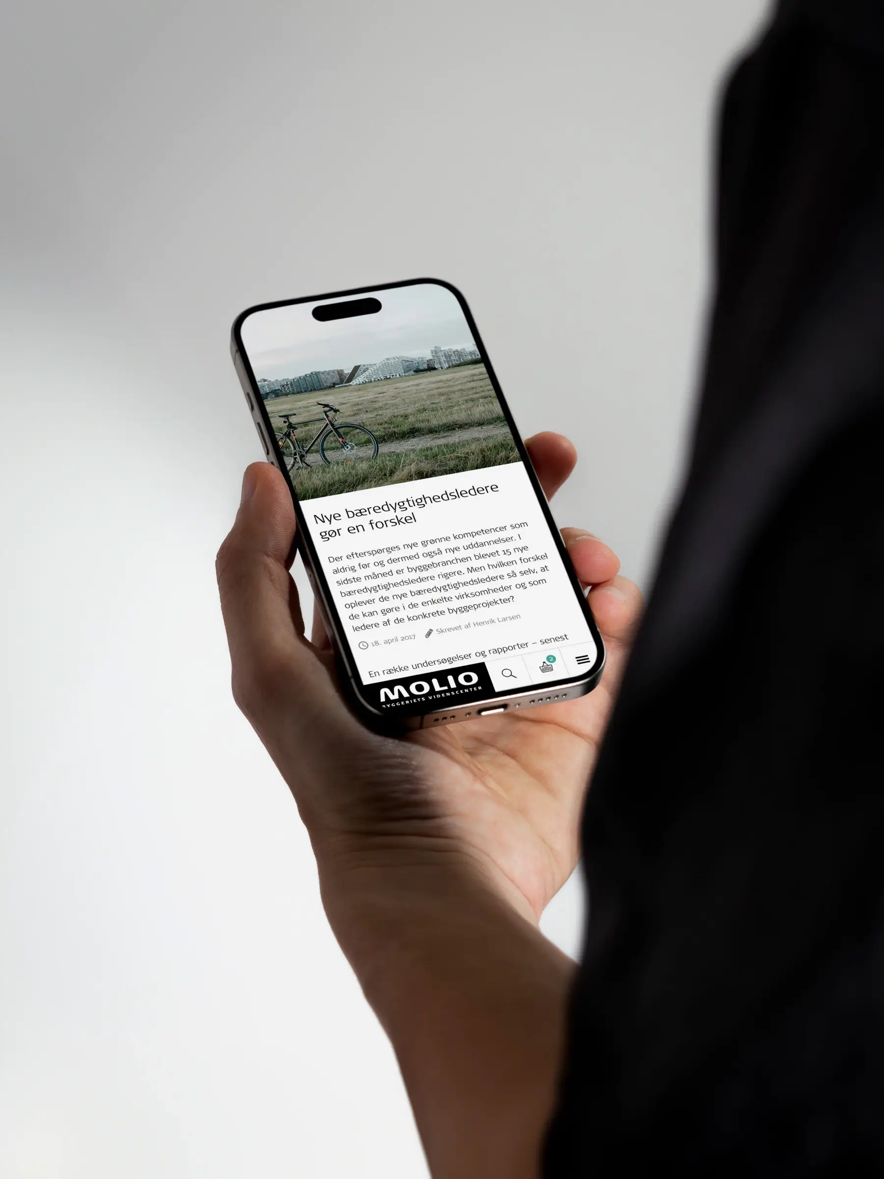 Molio mobile UI design shown on a hand-held iPhone, featuring header navigation and refined interface details that reflect thoughtful digital product design and mobile UX craftsmanship.