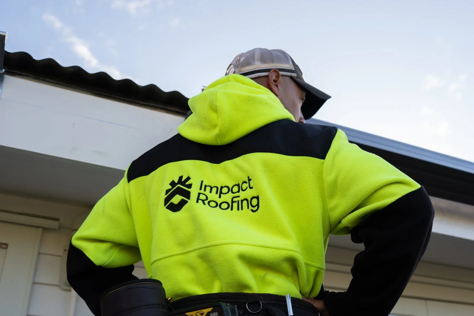 Impact Roofing roofer looking up at the roofline of a weatherboard house