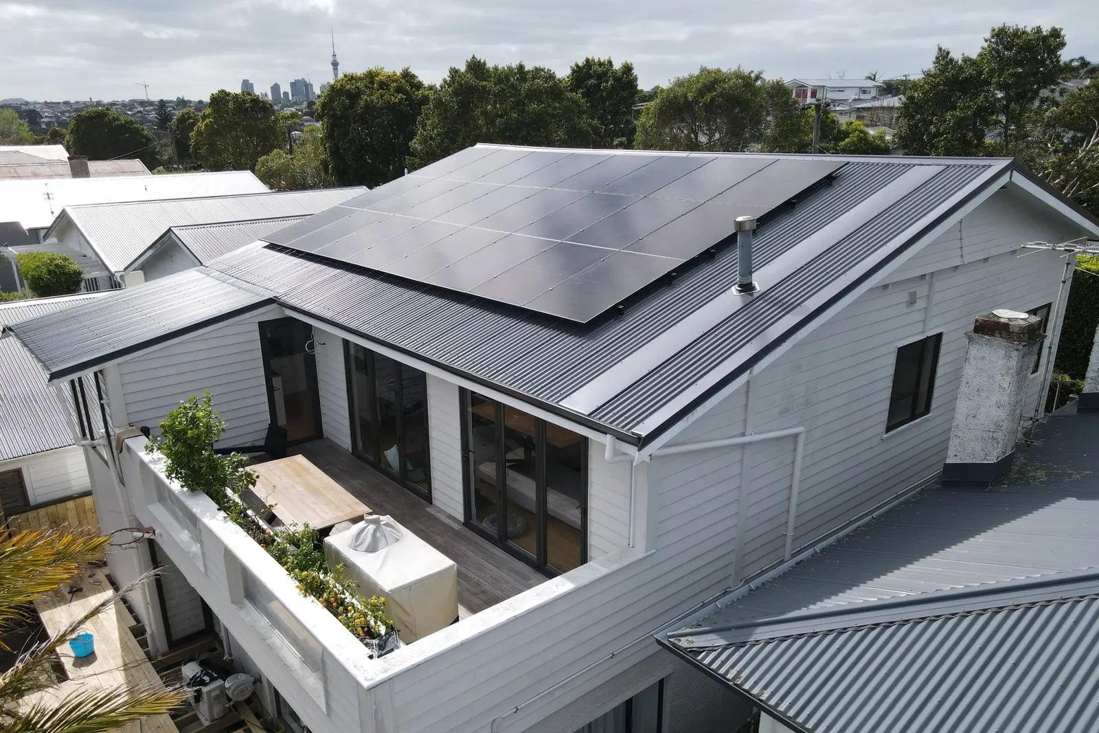 New metal roof with solar panels on an Auckland weatherboard home, with the Sky Tower in the distance
