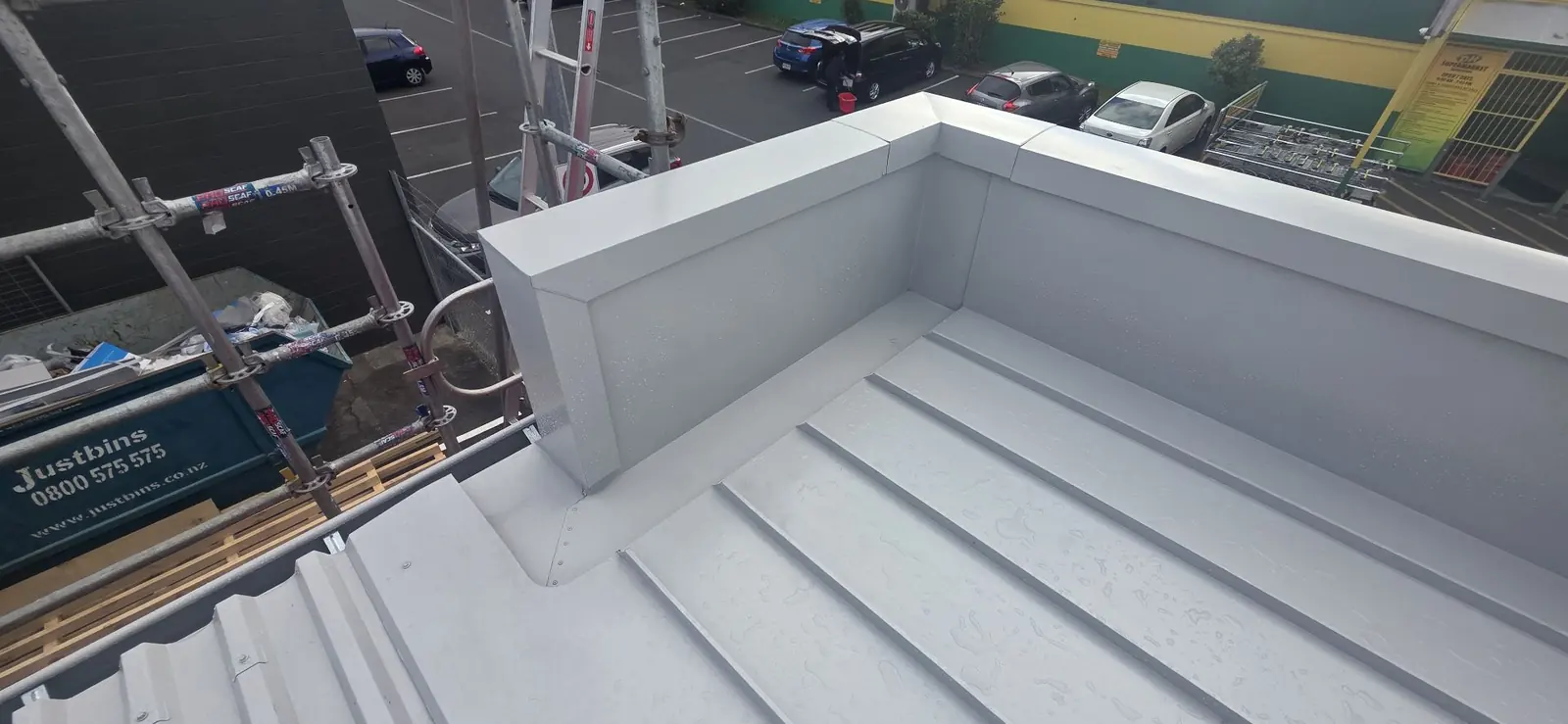 New internal gutter and parapet flashings on a commercial reroof, with scaffolding along the roof edge
