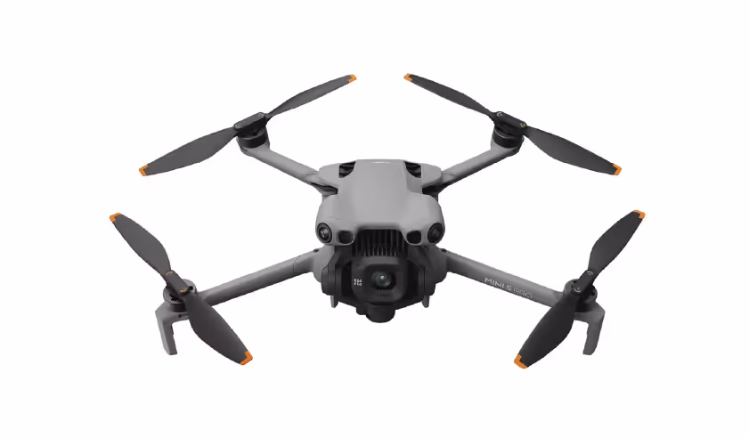 Graue Drohne mit vier Propellern und integrierter Kamera auf weißem Hintergrund.