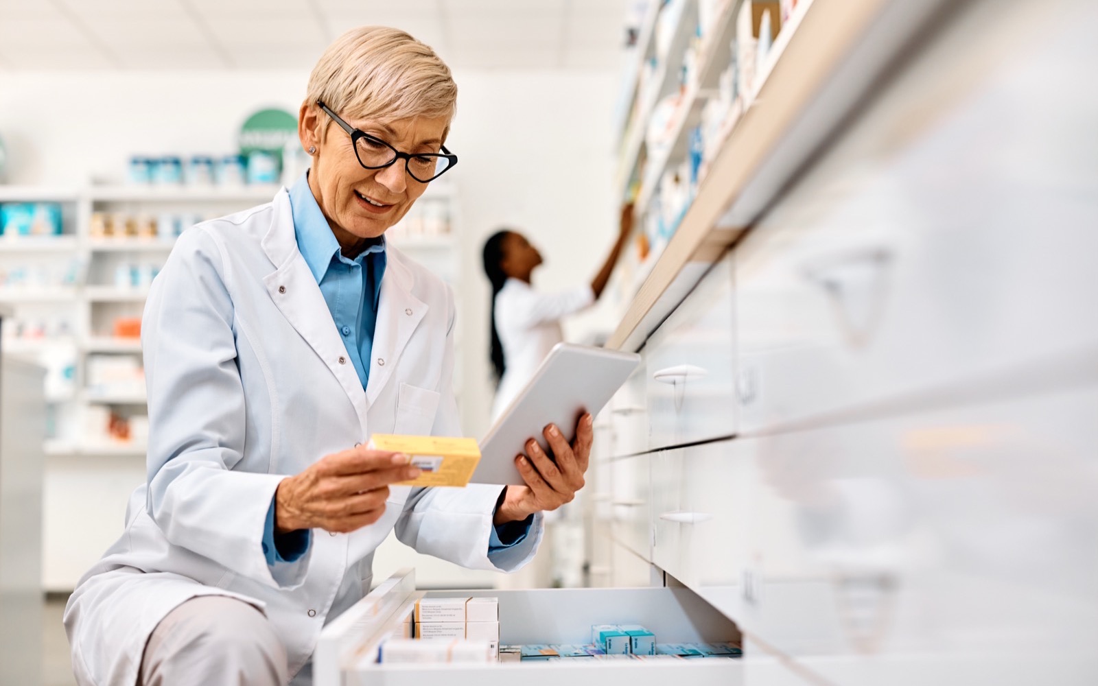 Pharmacienne qui vérifie une boîte de médicament sur sa tablette