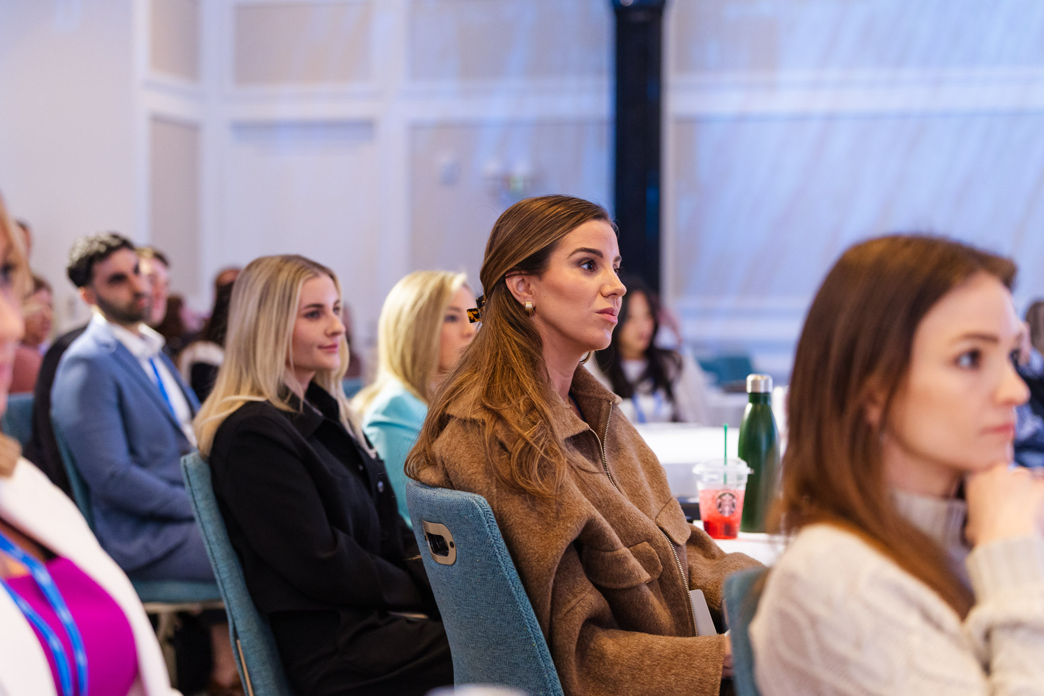 Diverse group of adults attentively listening at an indoor seminar or conference.