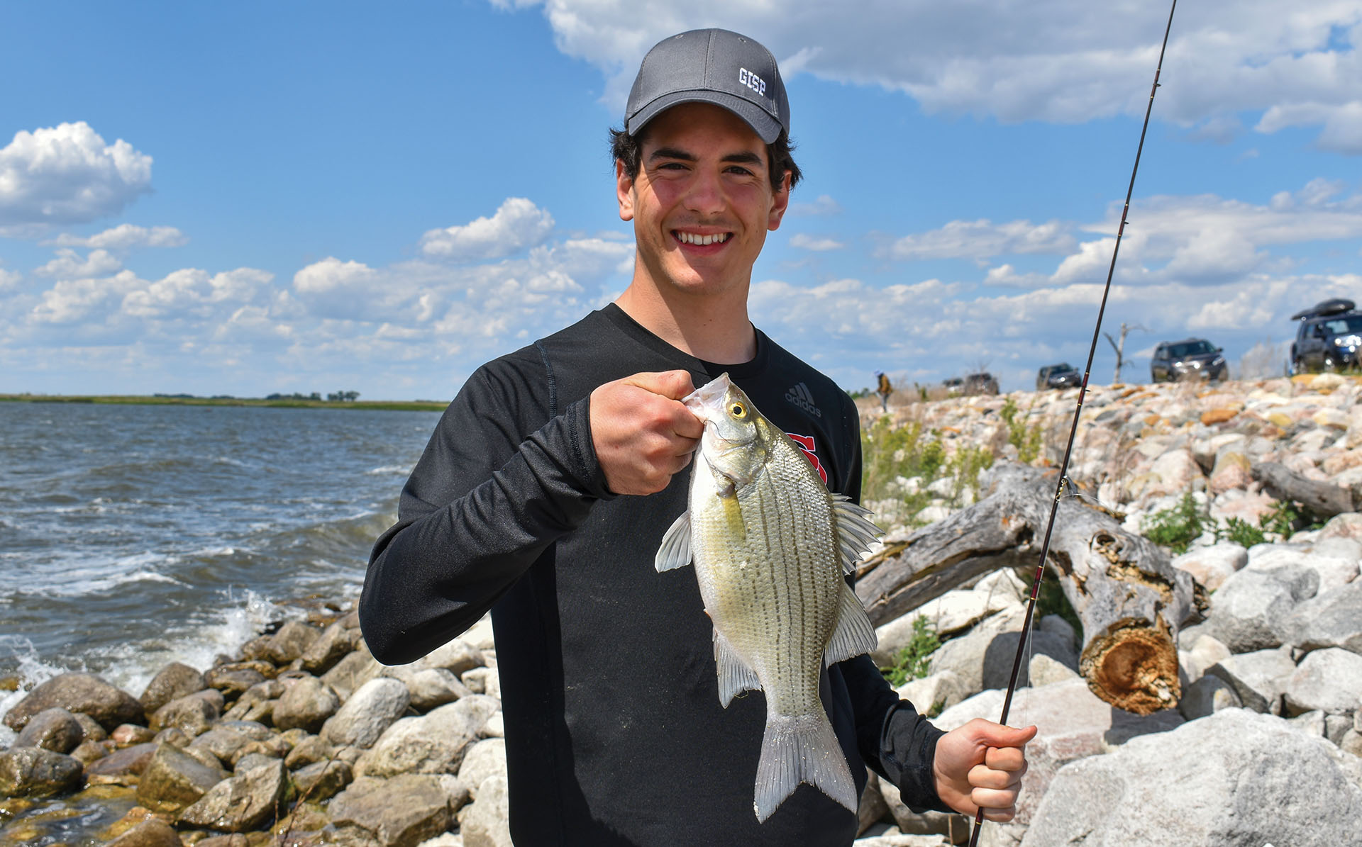 A young man holds a trout. 