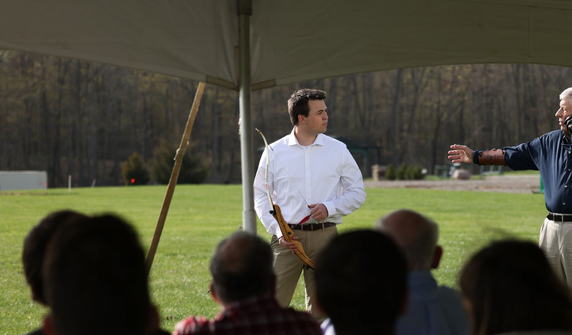 An archery instructor demonstrates technique. 