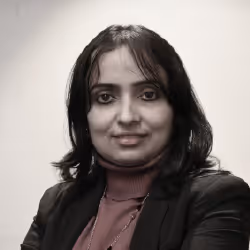 Portrait of a woman with shoulder-length black hair wearing a maroon top and black blazer, smiling softly.