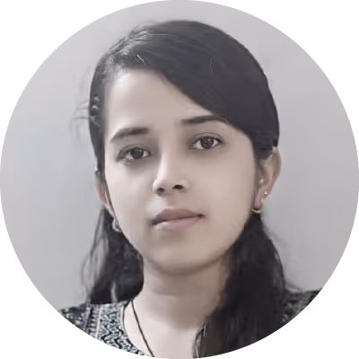 Portrait of a young woman with dark hair, wearing small hoop earrings and a patterned top, against a plain light background.