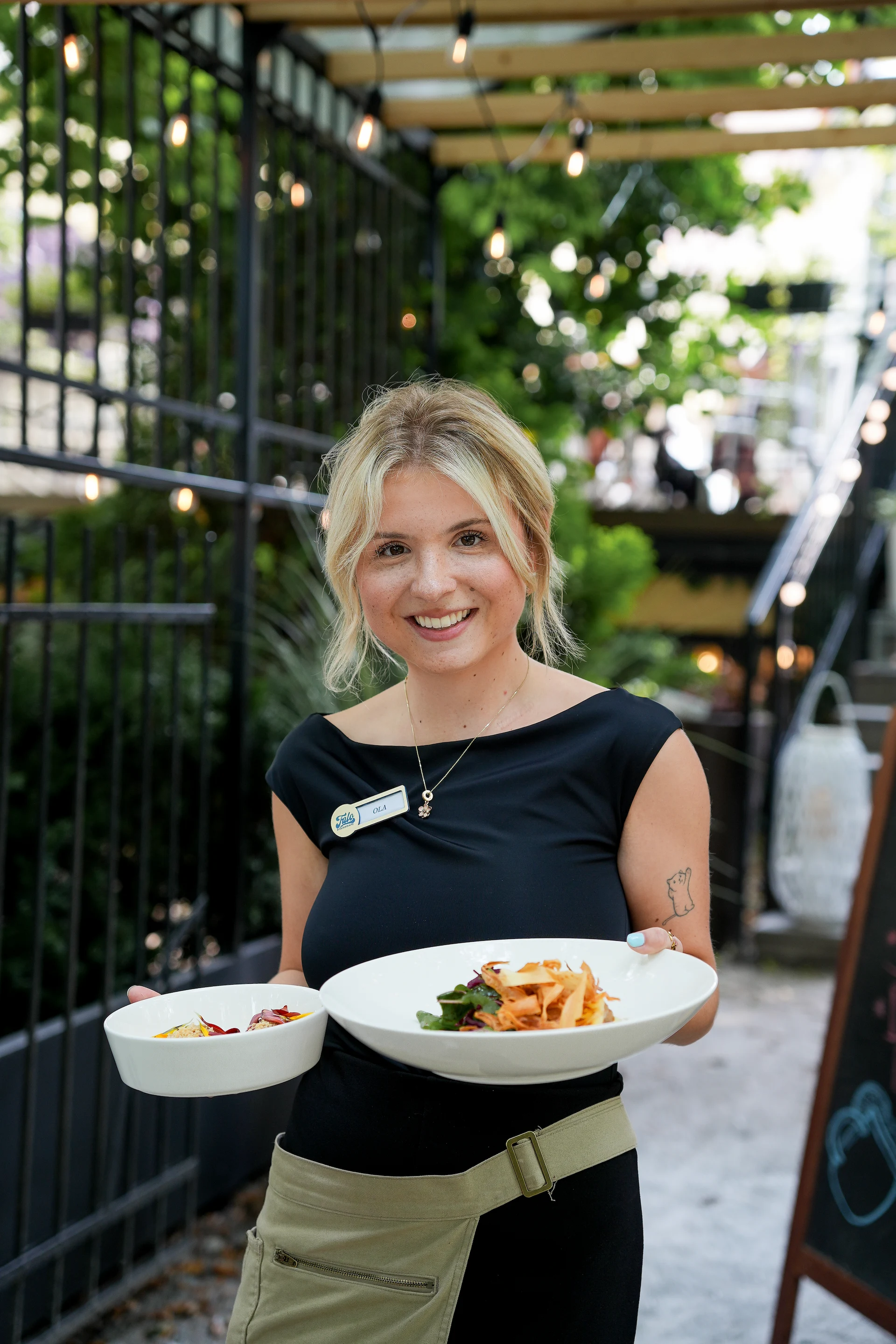 a blonde woman carrying two plates with a delicious food