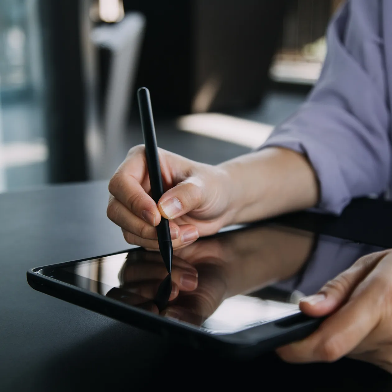 A person writing on a tablet with a pen.
