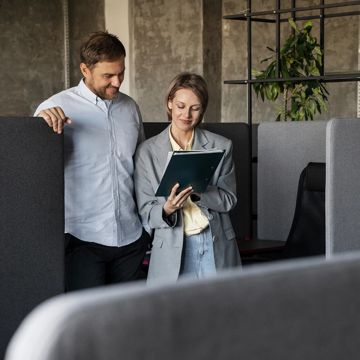 A man and a woman standing in an office cubicle.