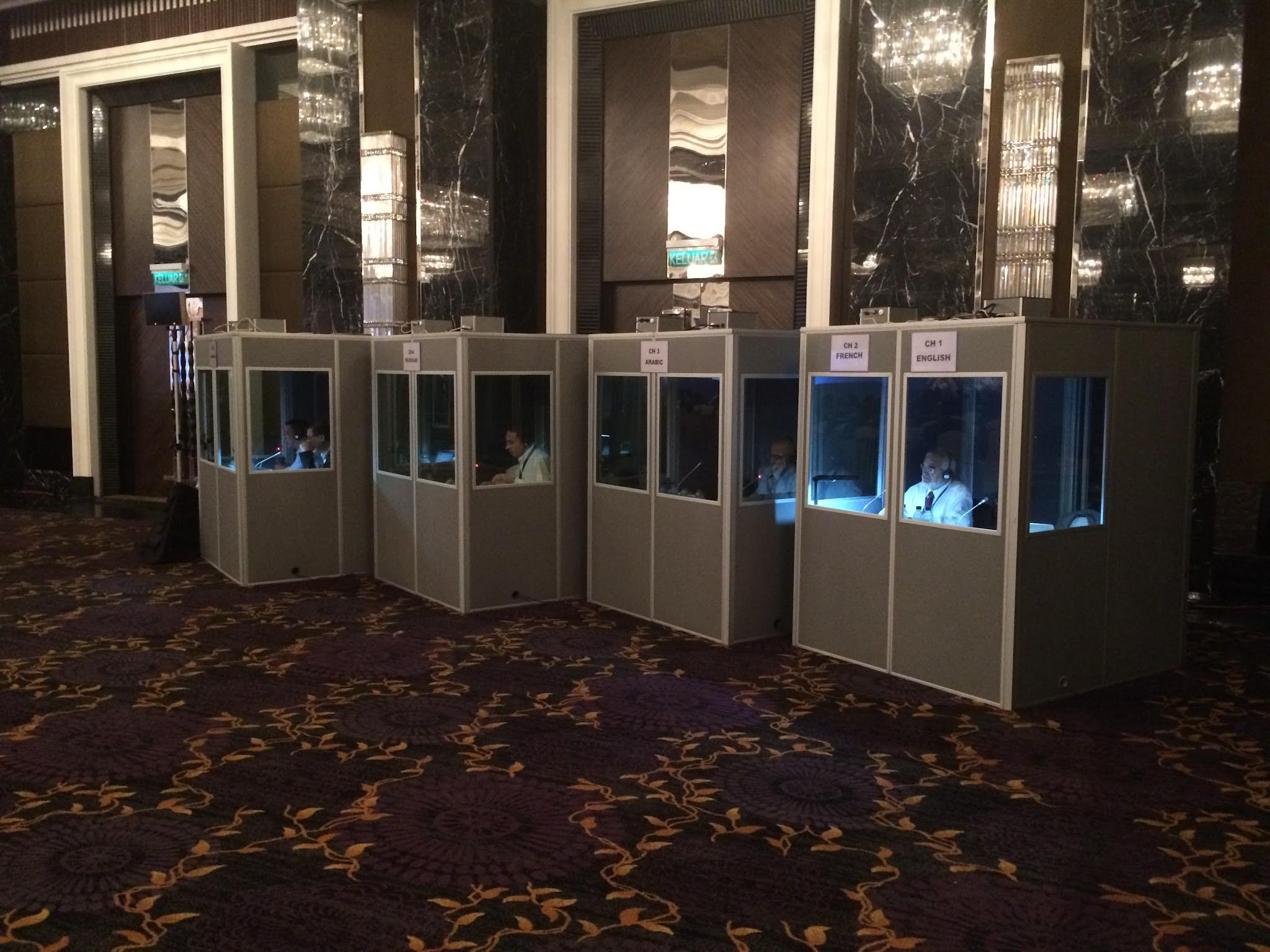 Four interpreter booths set up in a hotel foyer with interpreters at work