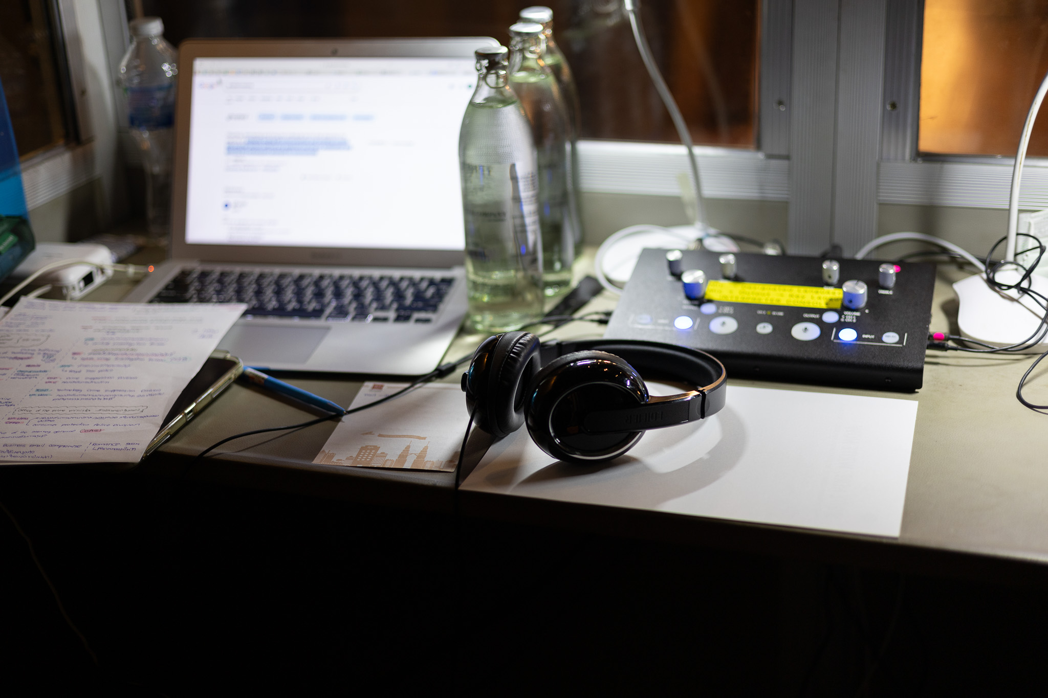 Interpreter console, headset and laptop on a desk inside a booth