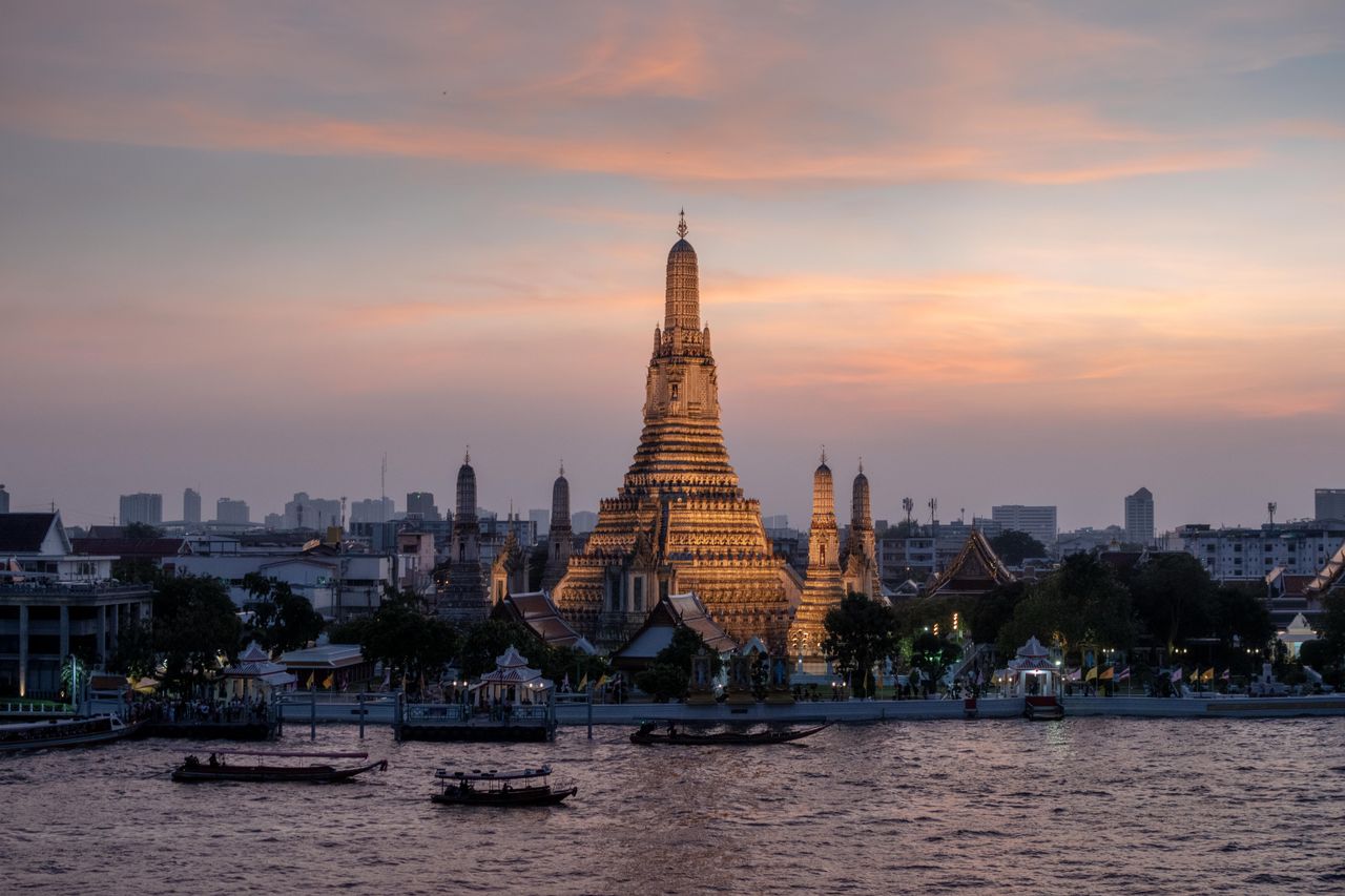 Wat Arun temple beside the Chao Phraya river in Bangkok at sunset