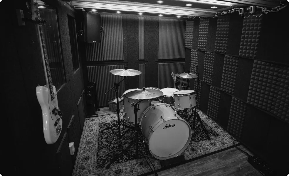 Drum set and bass hanging on the wall inside a large soundproof music booth made by WhisperRoom.