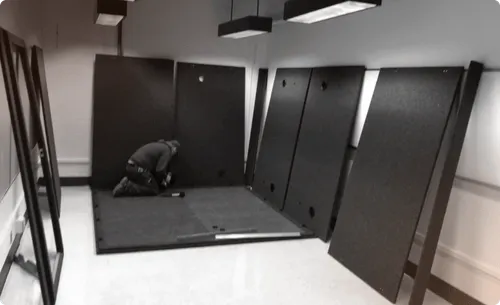 A large WhisperRoom sound booth being installed to illustrate the flexible setup for music schools, with one person performing the assembly in a college music facility.