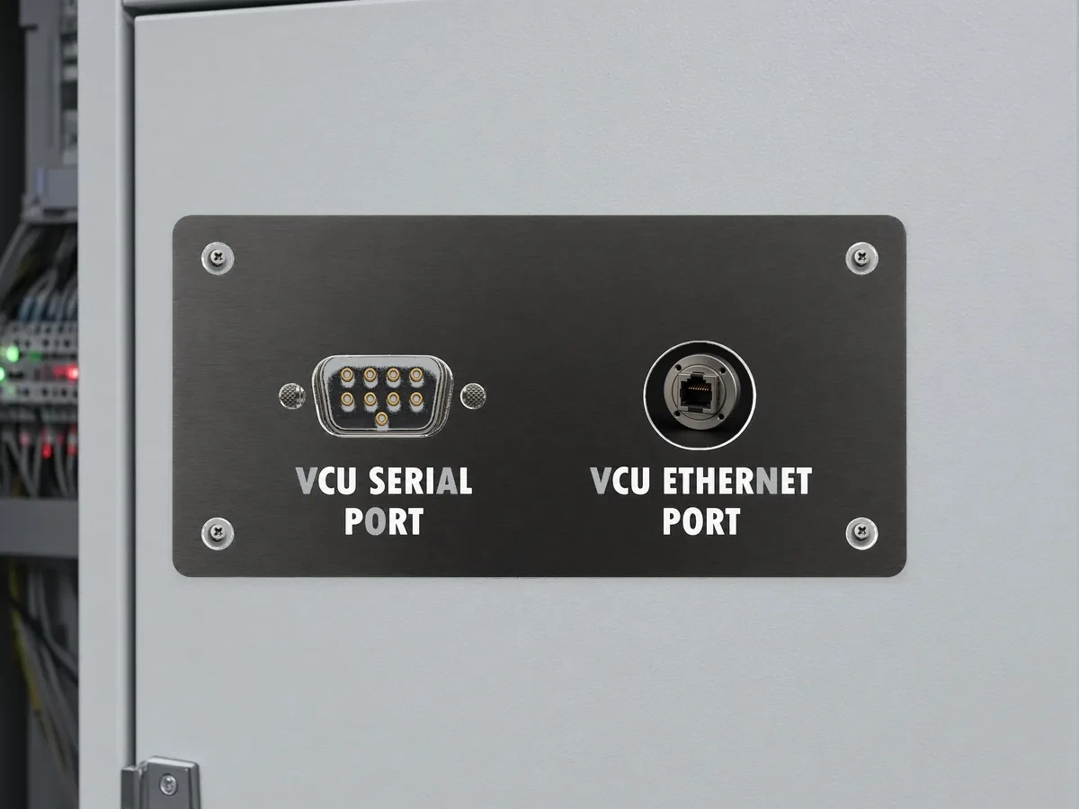 Black anodized aluminum control-enclosure port faceplate on an electrical control cabinet.