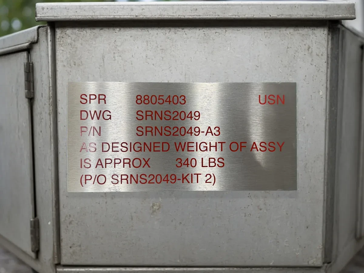 Riveted stainless capacity and weight data plate on heavy work-vehicle equipment.