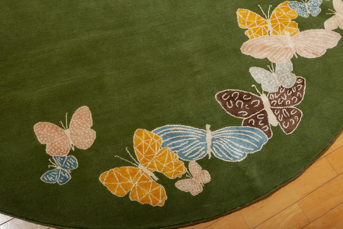 Detail of cream, blue, and brown butterfly cluster, showing fine linework and material contrast on luxury handmade rug.