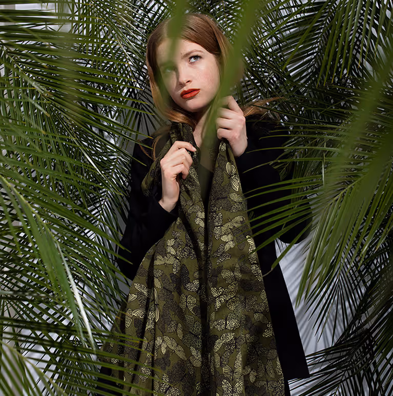 Model wearing Butterfly Scarf Green Silk by Sergio Mannino Studio among tropical palm leaves