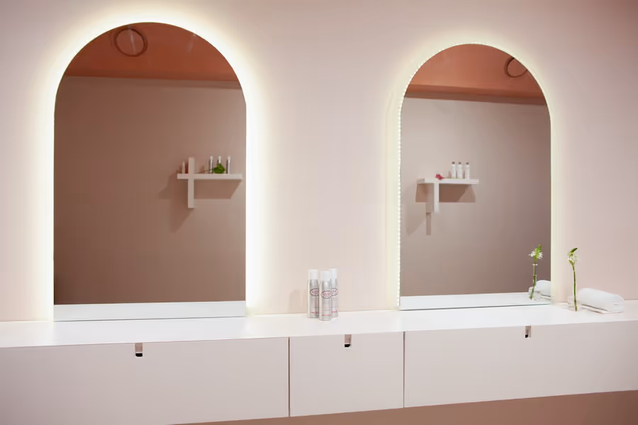 Hair salon interior design: counter with two mirrors. Smooth delicate blush wall colors and white lacquer