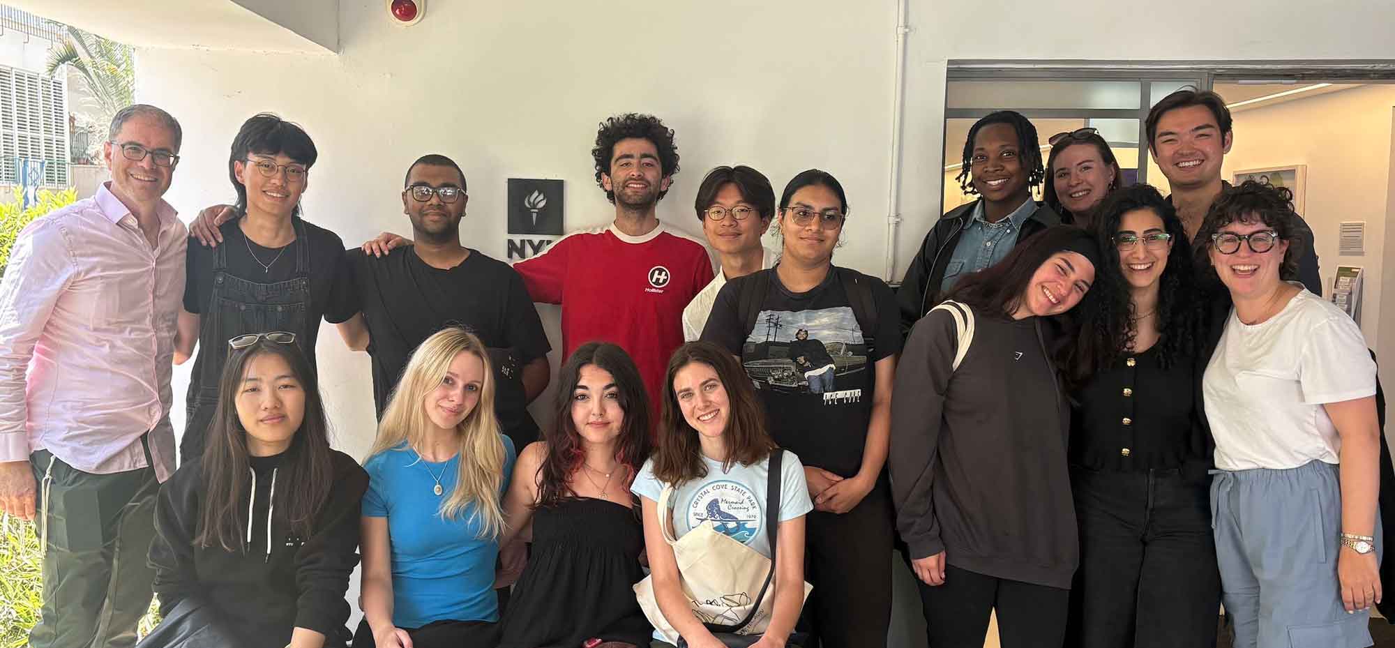 Group photo of NYU students and faculty posing outside a campus building.