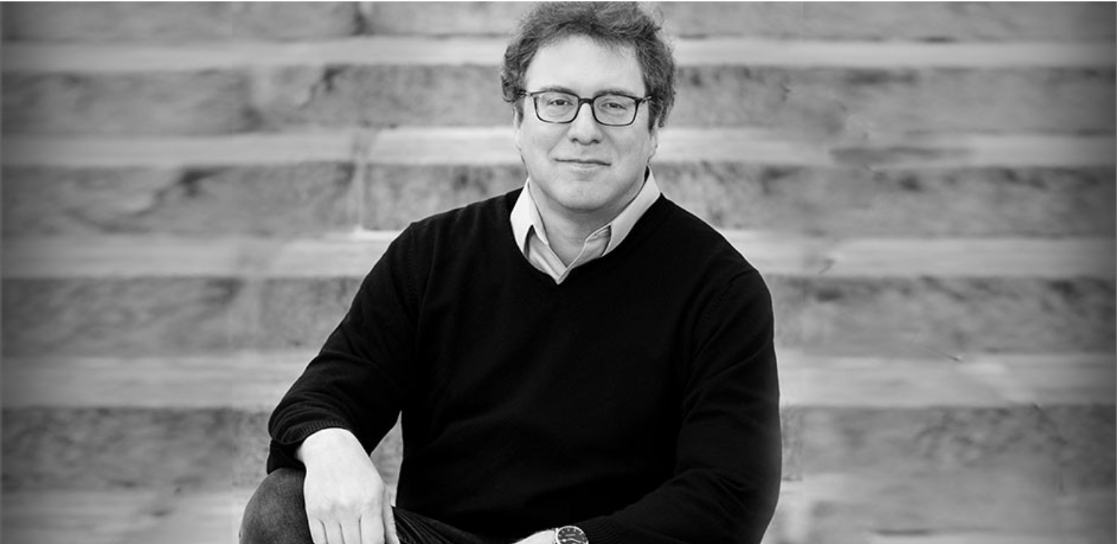 Man with glasses looking at at the camera with stairs in the background.