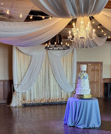 Gold backdrop with ceiling draping and cake table. 