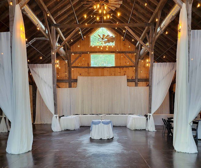 White two-tiered backdrop with wooden post framing and draping. 