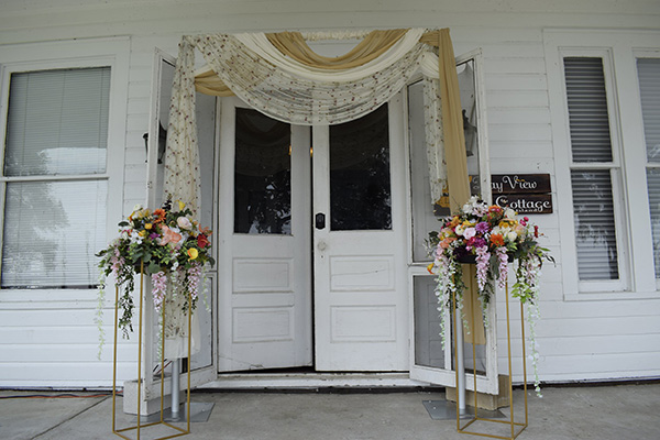 Door framing with multiple fabrics and flowers on gold stands. 