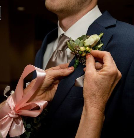 A hand is pinning a boutonniere.