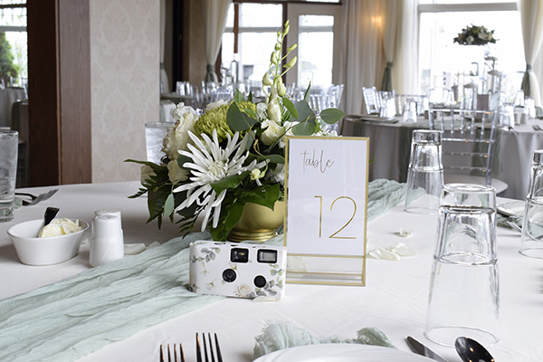 Flowers and camera with table number signage.