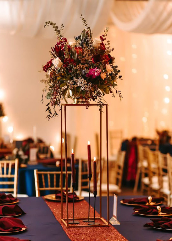 Fall floral centerpiece sitting on a gold stand.