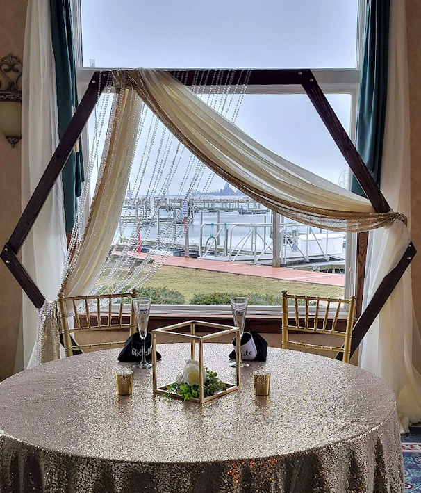 Dark wood arch decorated as a head table backdrop with gold fabric and crystal beads.