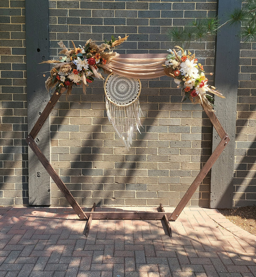 Bohemian styled, six-sided arch. Fabric, flowers, and dream catcher hanging. 