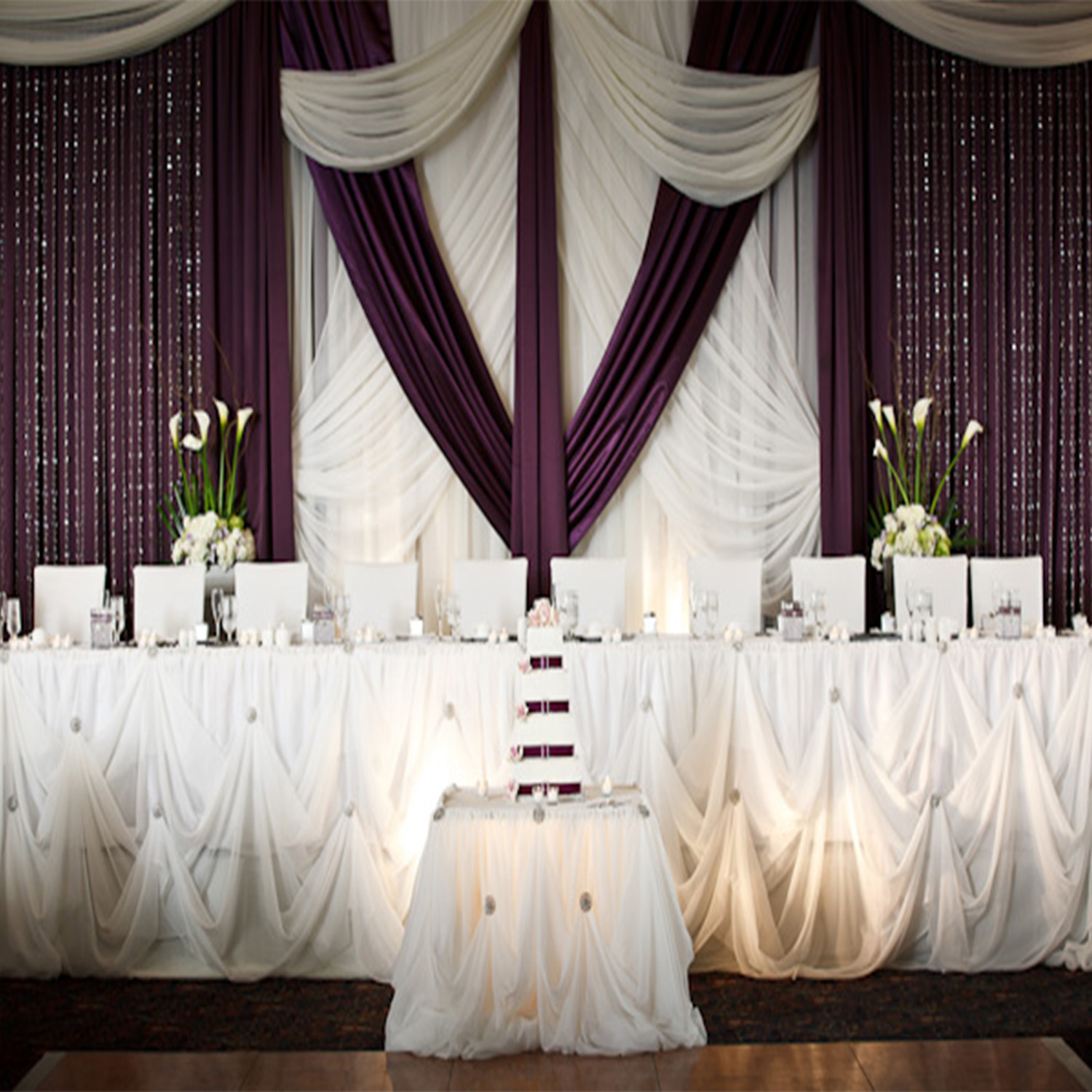 Purple and white fabric behind a head table with Cinderella skirting. 