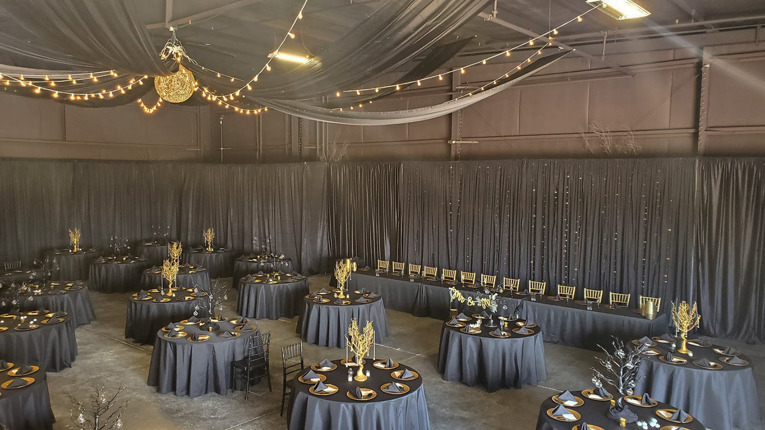Full Room Black Fabric Draping with gold chandelier and gold accents.