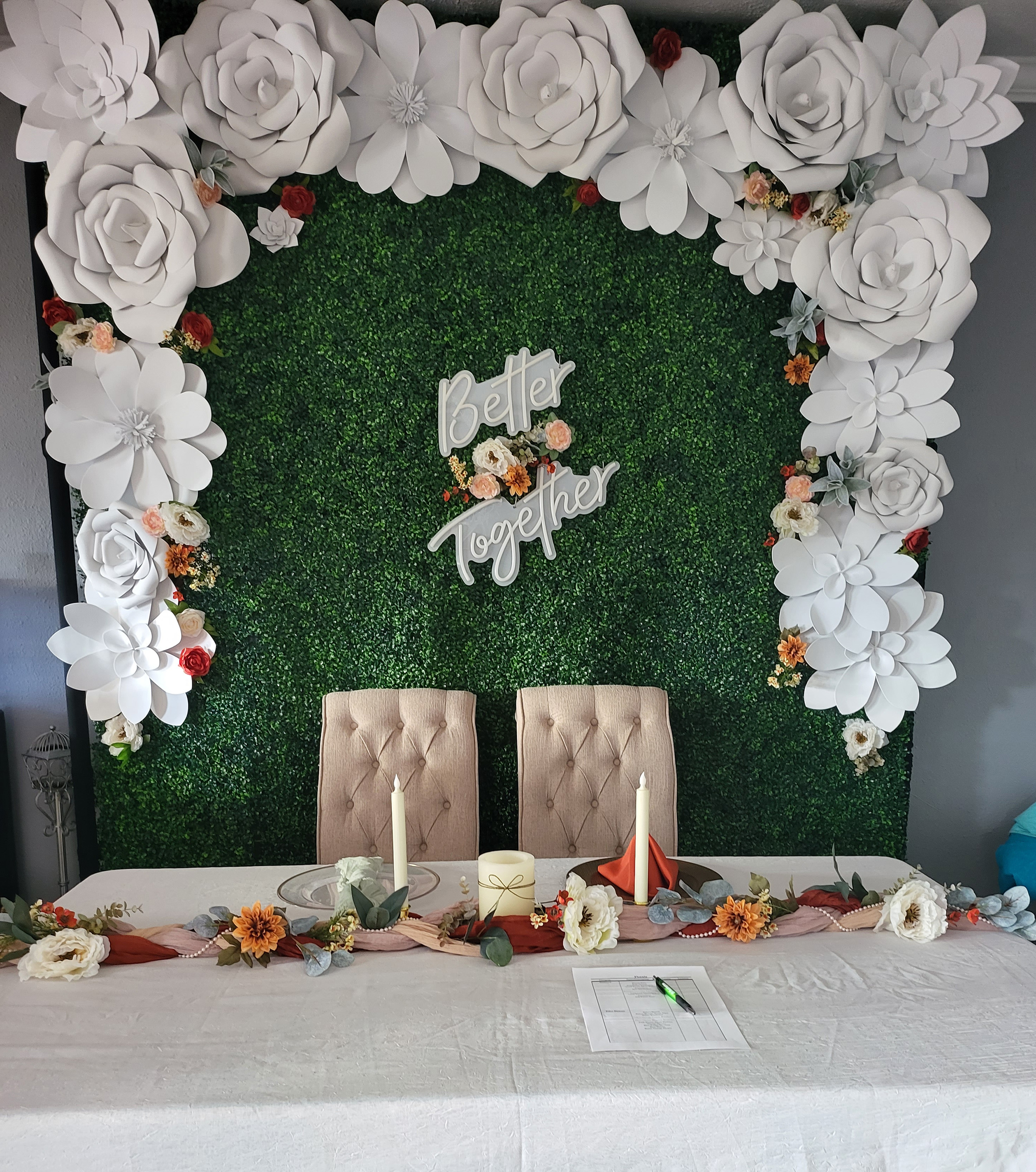 "Better together" LED sign positioned on a green box wall with huge white foam flowers.