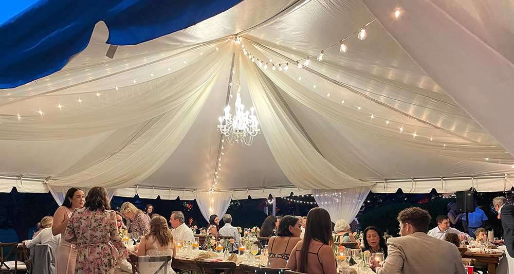 White fabric and bistro lights on a tent ceiling. 