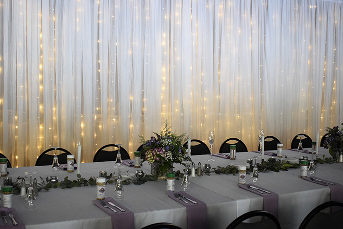 A head table with purple napkins and silver flatware.