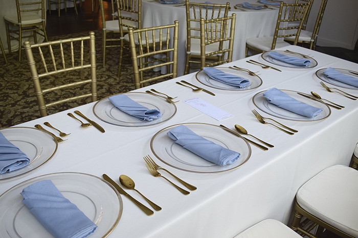 Gold Chiavari chairs with clear chargers and gold flatware at every seat. 