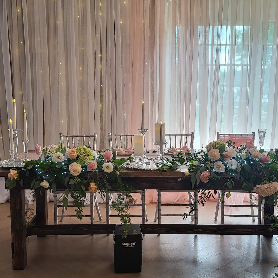 Wooden table with flowers and candles as head table decorations. 