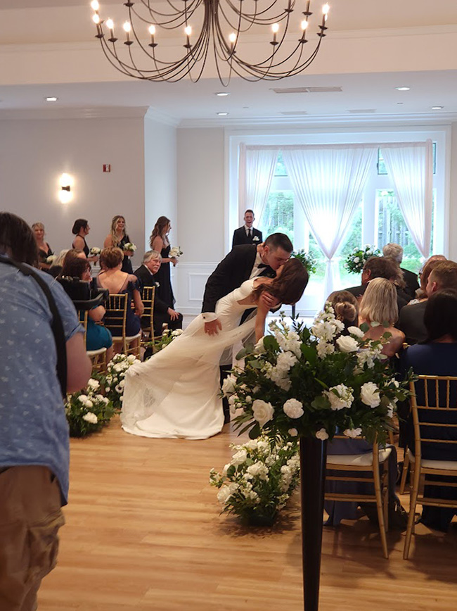 Bride and Groom share a kiss in the aisle. 