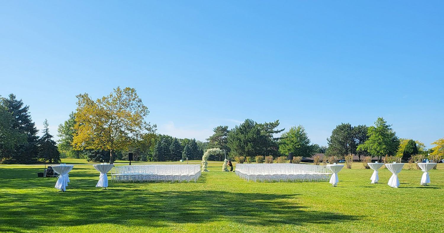White ceremony chairs, arch, and cocktail tables. 