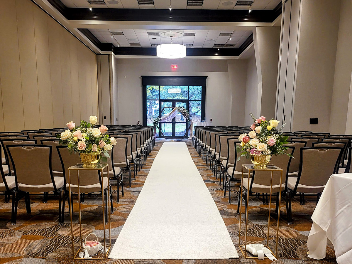 Ceremony with white aisle runner and aisle flowers. 