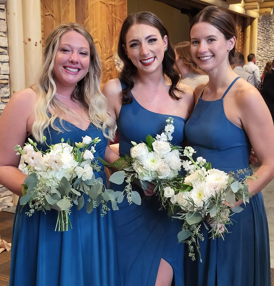 Three bridesmaids in royal blue holding bouquets. 