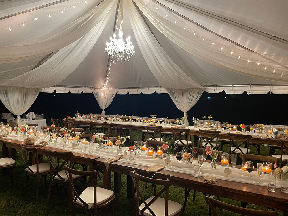 Italian family styled wedding reception in a tent with chandelier and centerpieces. 