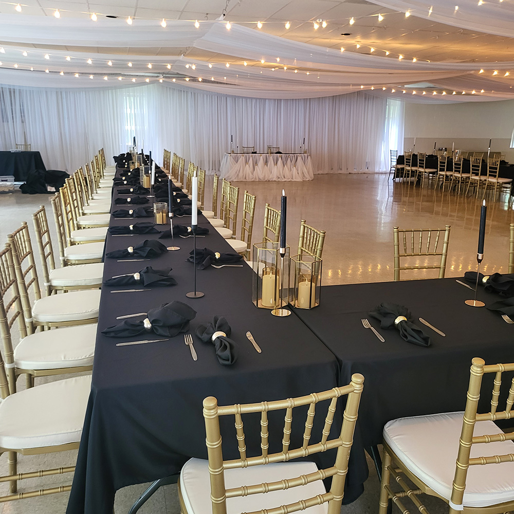 Black linens with gold candles and white wall draping.