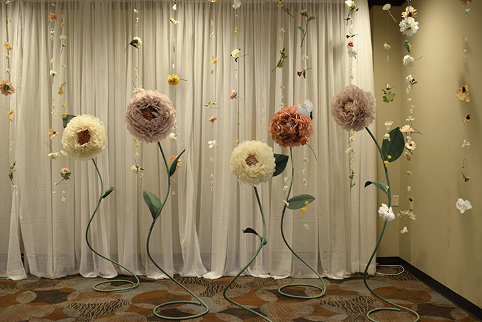 Wedding photo op corner of 5-6 foot tall flowers and mini flowers hanging from the ceiling. 