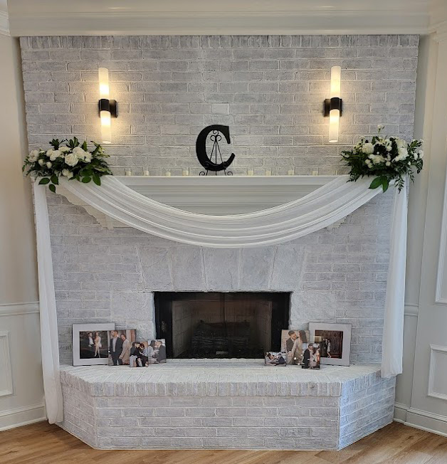 White fabric swag and floral arrangements on fireplace. 