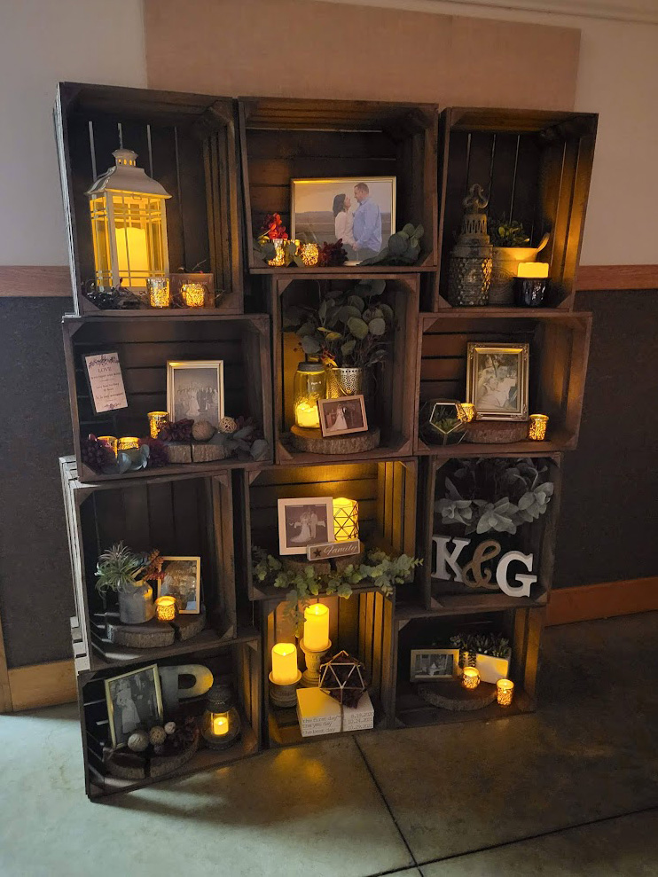 Memory photos and candles sitting in stacked apple creates. 